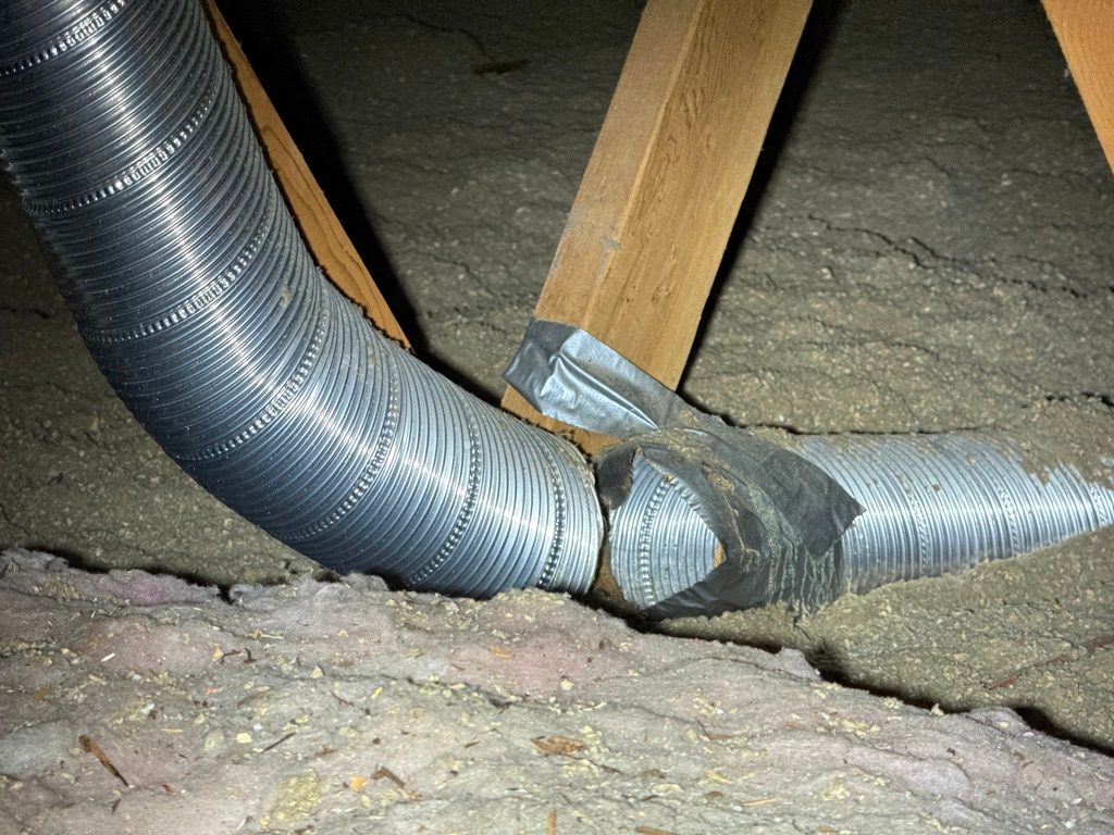Flexible exhaust duct in an attic separated at the joint, with old duct tape peeling away