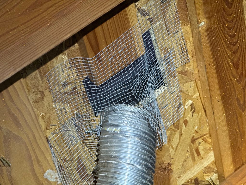 Attic vent duct at the roof with loose wire mesh stapled around it instead of a sealed connection